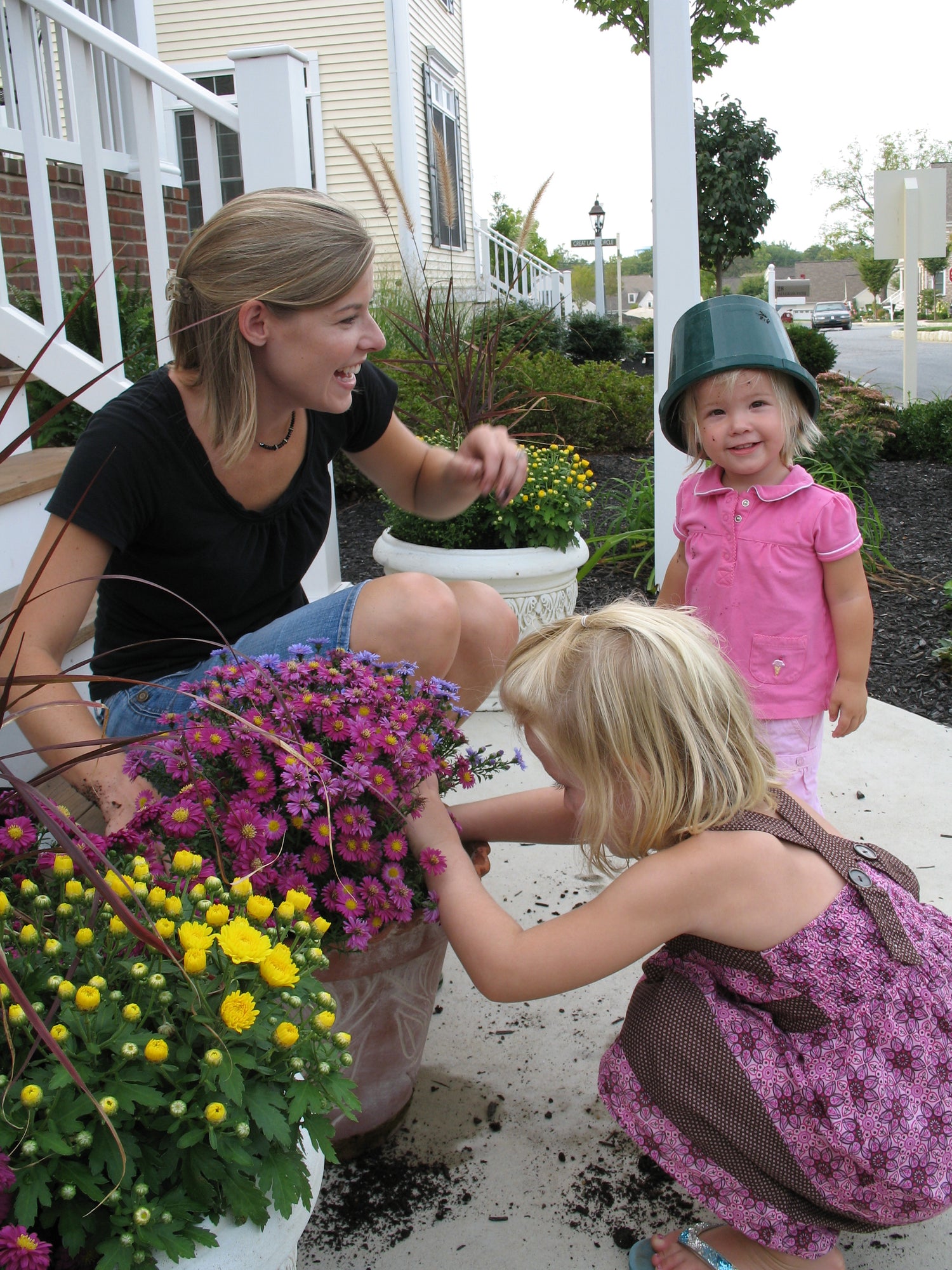 Mother and two children laughing while picking flowers in a beautiful garden.