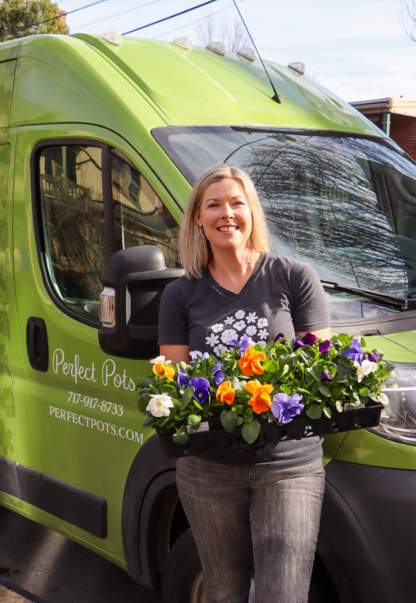 A woman smiling and holding a colorful bunch of flowers.